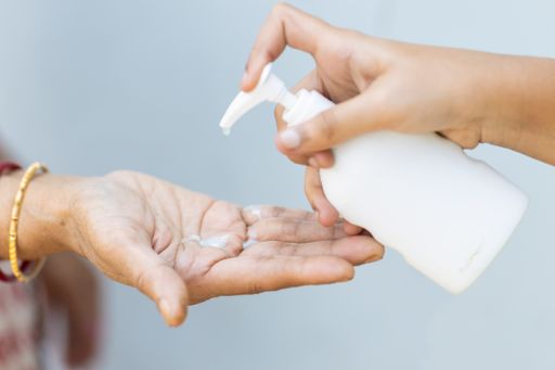 A closeup shot of a person pouring liquid soap into the hand of another person - importance of washing hands during the COVID-19 pandemic