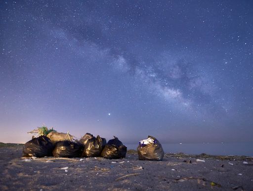 The bags with trash at the beach under the night sky full of stars
