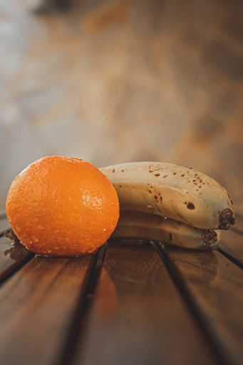 A closeup shot of a tasty looking tangerine and bananas  on a wooden table