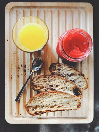 A vertical high angle shot of orange juice, jam, and slices of bread on a tray