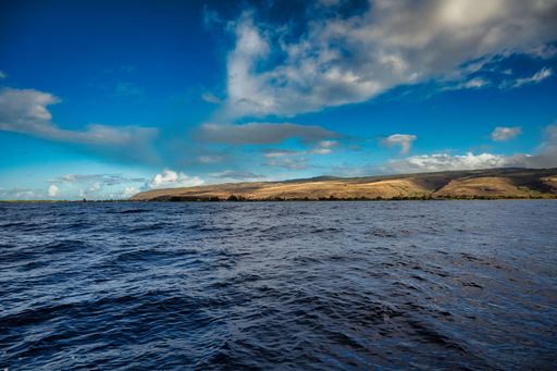 THE COAST LINE NEAR THE NA PALI COAST ON THE ISLAND OF KAUAI IN HAWAII WITH A NICE BLUE SKY AND CLOUDS.