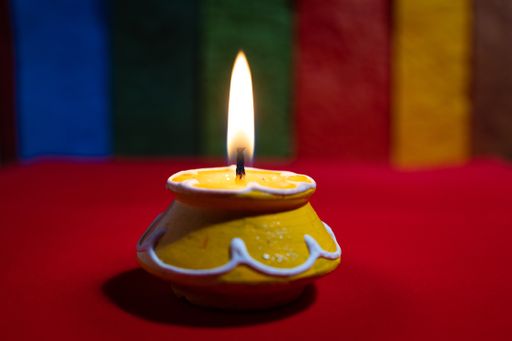 A closeup shot of a small yellow handmade candle on a red surface