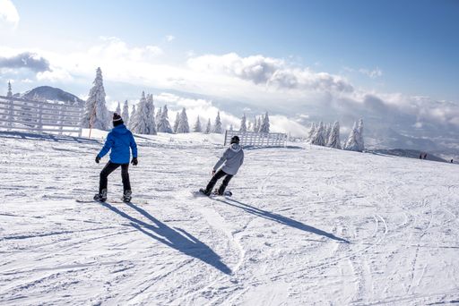 Two male snowboarders riding down the slope with a beautiful winter landscape in the background
