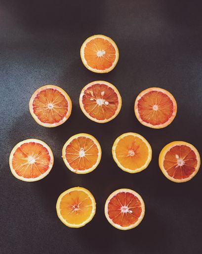 A vertical high angle shot of sliced oranges on a black surface - great for a creative wallpaper