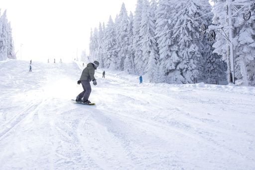 A snowboarder in motion riding down the hill in the mountain resort
