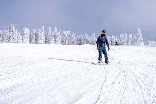 A male snowboarder riding down the slope with a beautiful winter landscape in the background