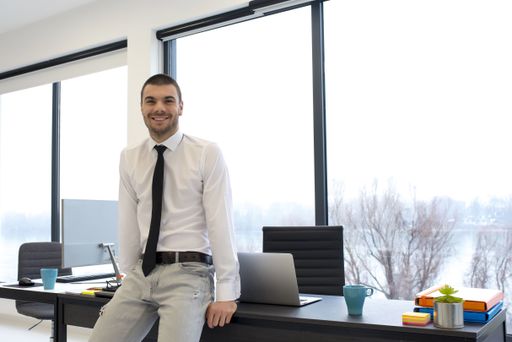 A young male entrepreneur leaning on his desk at the office