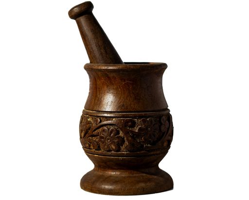 An isolated shot of a wooden mortar and pestle with intricate designs on a white background