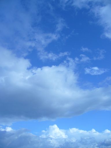 A vertical shot of the blue sky with white clouds