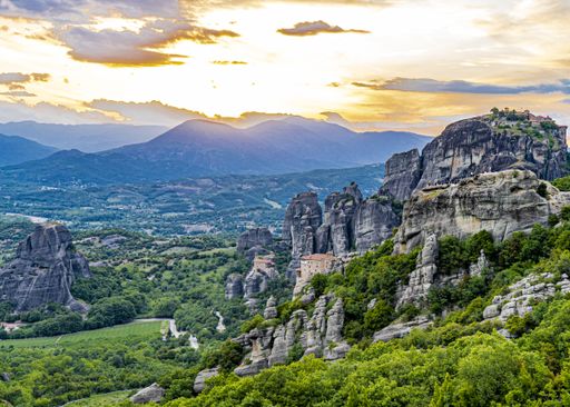The image shows a sunset in the Meteora region of Greece looking beyond the Monasteries   in the rock formations typical of this region
