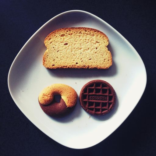 A high angle shot of toasted bread, donut, and chocolate on a white ceramic plate