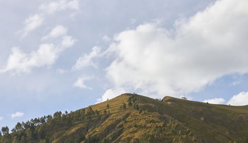 A panoramic view of a hill with a cloudy day background