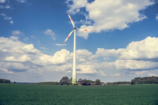 A wind turbine in the middle of a field against a cloudy sky