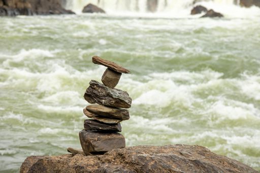 A close-up of stones stacked on top of each other against river background