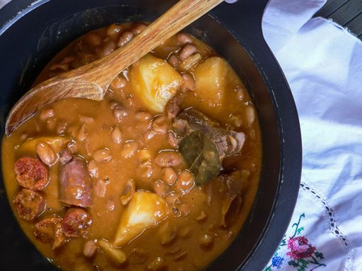 A top angle shot of soup with beans, meat and potatoes in a saucepan