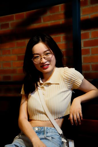 A portrait of a beautiful young Chinese girl in eyeglasses against the brick wall