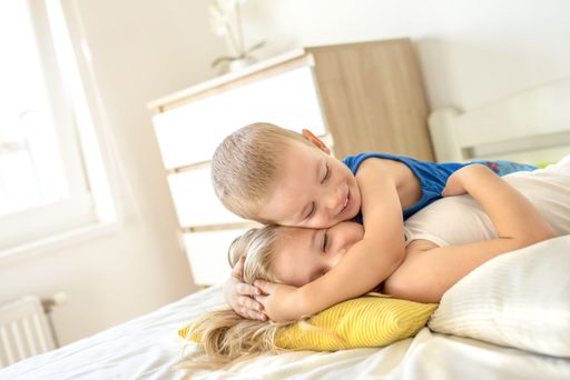 A closeup shot of blonde children playing with pillows on the bed in the room