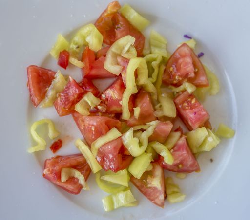 An overhead shot of cut tomatoes and green peppers in a white plate