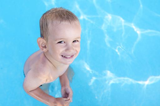 A high angle shot of a smiling young blond boy in the swimming pool