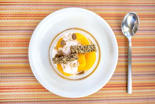 A closeup shot of apricot compote with vanilla cream with oat flakes and sesame sticks