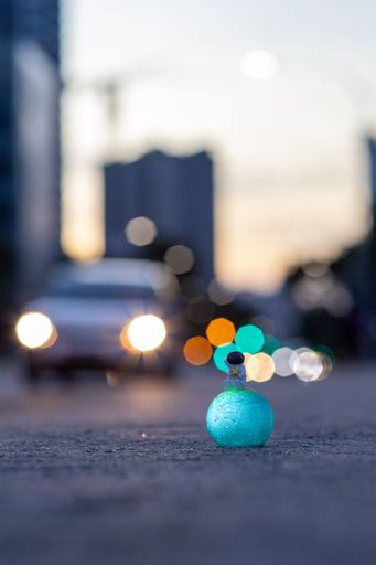A vertical shot of an astronaut figurine on the road with bokeh lights