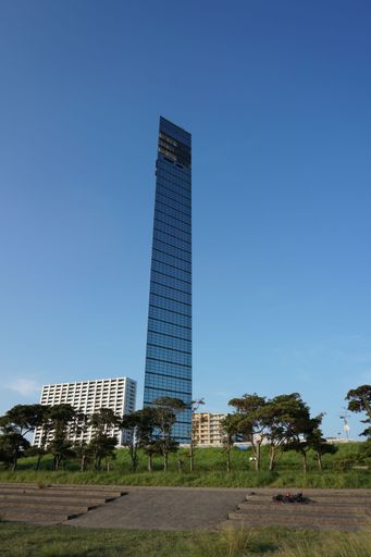 A vertical shot of a skyscraper and residential buildings in a city