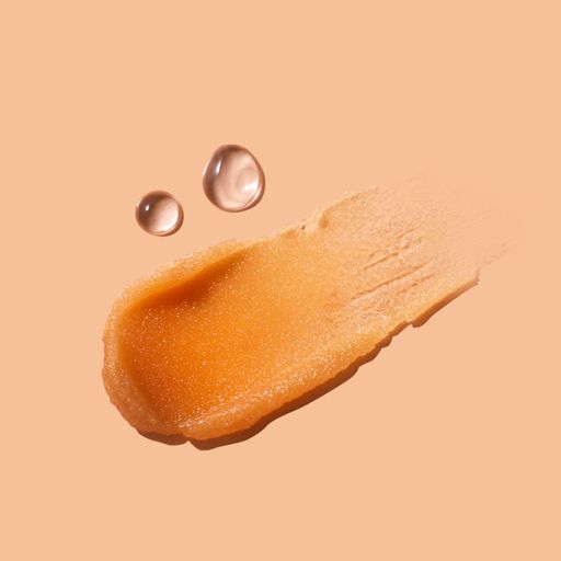 A closeup shot of a makeup smear of a creamy luminous blusher on a beige background