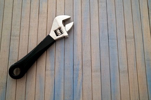 A closeup of an adjustable wrench on a wooden table