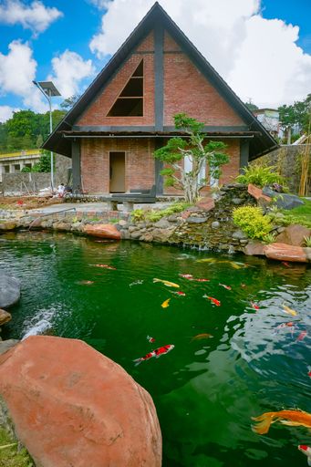 A vertical shot of a beautiful house with koi fish in the pond in the garden