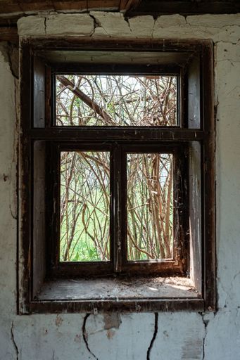 A vertical shot of a window of an old abandoned house from the inside