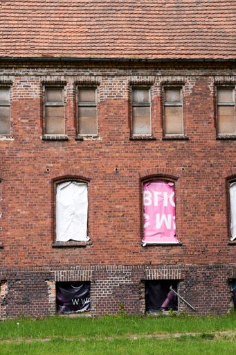 A vertical shot of an abandoned psychiatric department building in Poland with brick walls and empty windows