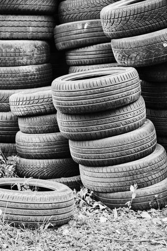 A vertical grayscale shot of many used old car tires