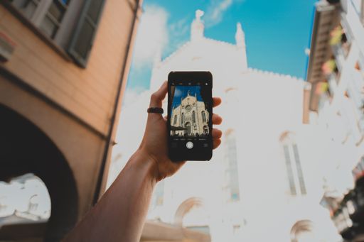 A vertical shot of a person with a smartphone taking a picture of a concrete architectural structure