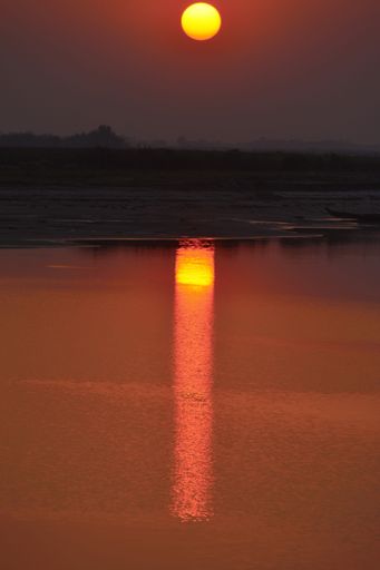 A vertical shot of the Sun shining in the sky on a vibrant sunset in a rural area