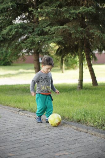 Three years old child playing with a ball on a street in the city