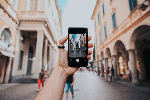 A selective focus shot of a person taking a photo of the city with a black phone