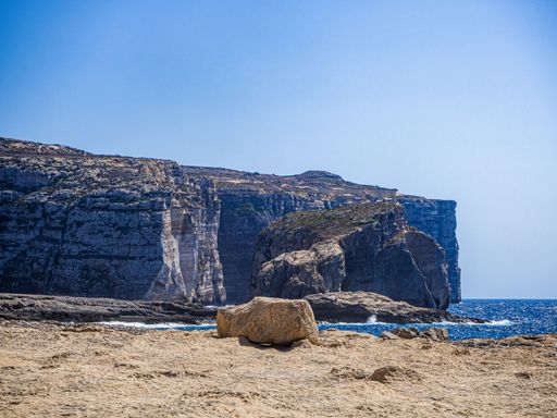 An aerial view of rocks in sandy beach surrounded by water