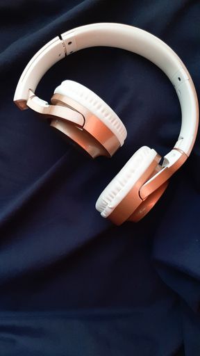 A vertical closeup shot of white headphones on blue background