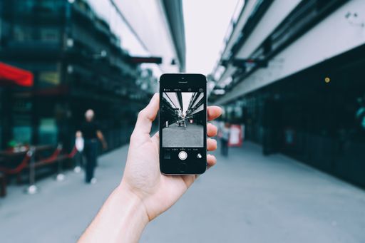 A tourist with a smartphone taking a picture of the beautiful view with high buildings under the cloudy sky