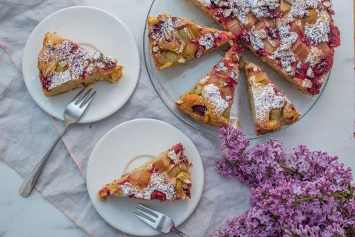 A top view of rhubarb pie slices on plates on a table along with flowers