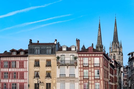 Bayonne in the pays Basque, typical facades with colorful shutters in the historic center, with the cathedral Sainte-Marie in background