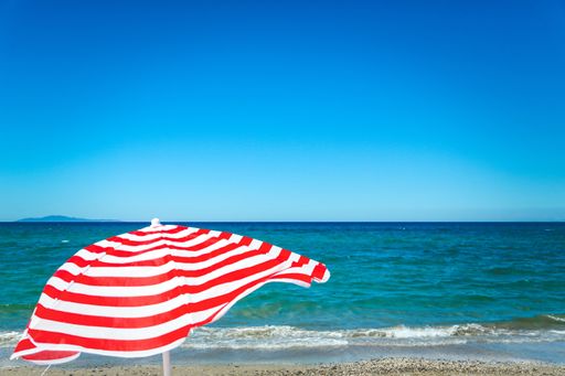 A red and white striped parasol on the beach near the beautiful sea