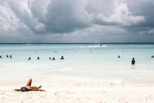 A beautiful shot of people on the beach enjoying the beautiful view of crazy clouds and the warmth of sun
