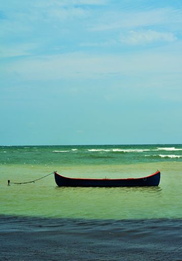 A vertical shot of a small boat anchored in the turquoise sea
