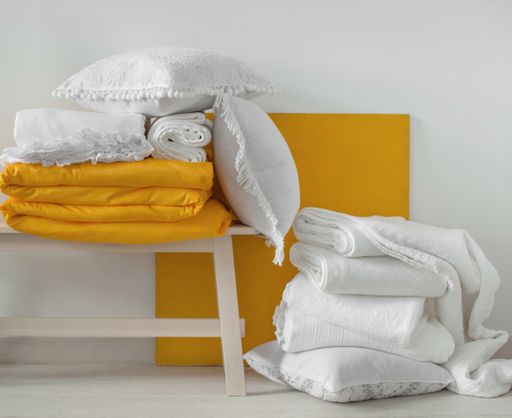 Soft yellow and white decorative pillows and blankets in the bedroom