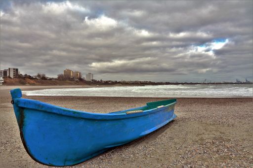 A closeup shot of a small blue boat on the beach on a cloudy day