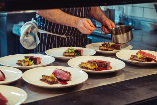 A closeup shot of the hands of the chef preparing a fine dinner in the kitchen of a restaurant in London, England