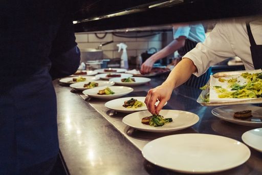A closeup shot of the chefs preparing a fine dinner at the kitchen in a restaurant in London, England