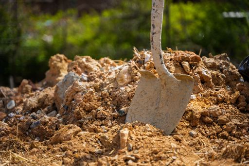 A closeup shot of a shovel stuck in dirt on a construction site
