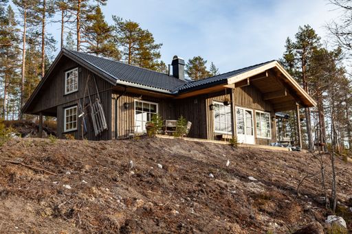 A wooden building on a hill in a forested area under the bright sunlight